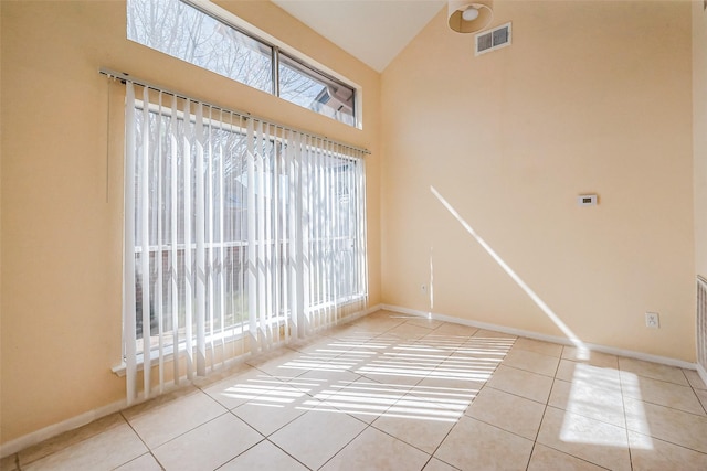 tiled spare room featuring baseboards, visible vents, and high vaulted ceiling