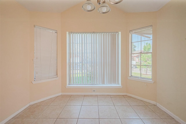 tiled spare room with baseboards, lofted ceiling, and an inviting chandelier