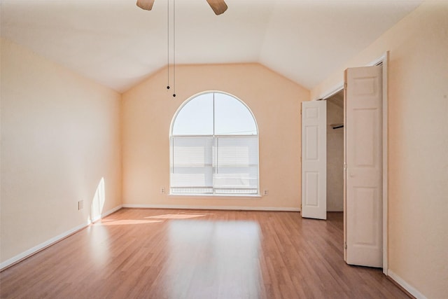 empty room with vaulted ceiling, baseboards, a ceiling fan, and wood finished floors