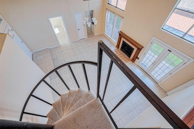 stairs featuring tile patterned flooring, a wealth of natural light, a fireplace, and a towering ceiling