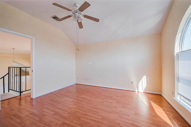 unfurnished room with visible vents, baseboards, lofted ceiling, wood finished floors, and a ceiling fan