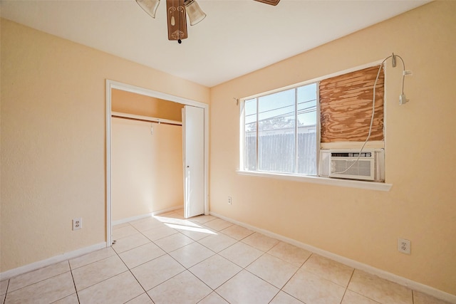 unfurnished bedroom featuring tile patterned floors, a closet, baseboards, and cooling unit