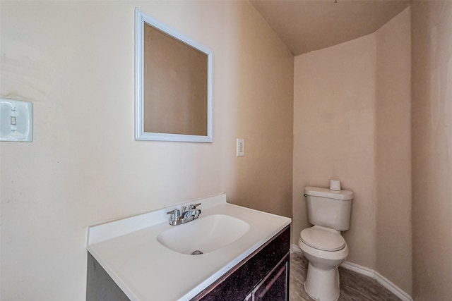 bathroom featuring baseboards, toilet, and vanity