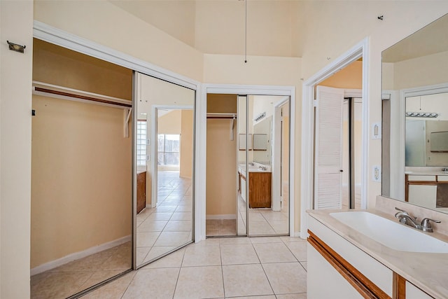 full bathroom featuring vanity, tile patterned floors, a spacious closet, and baseboards