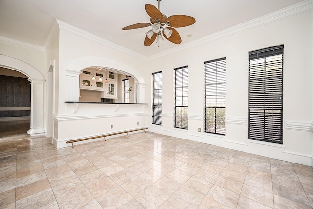 empty room featuring a ceiling fan, crown molding, and baseboards