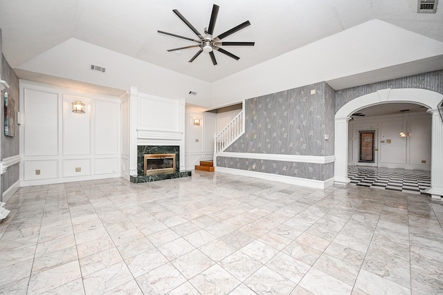 unfurnished living room with arched walkways, a decorative wall, a fireplace, a ceiling fan, and visible vents