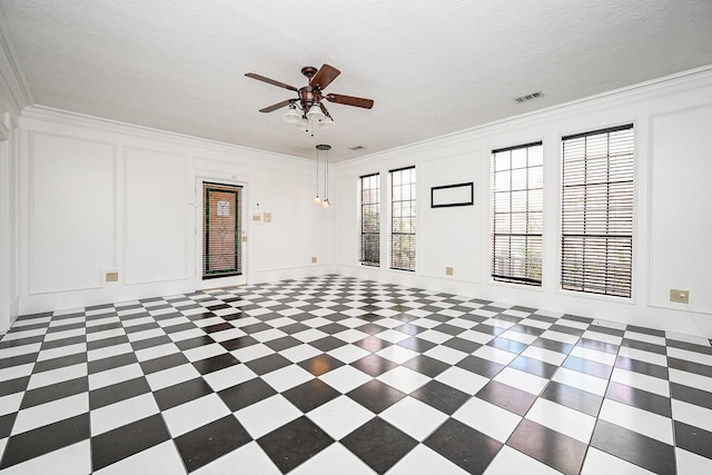 empty room with crown molding, visible vents, a decorative wall, and a textured ceiling