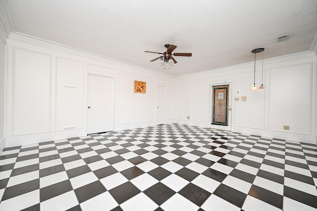 empty room with crown molding, a textured ceiling, a ceiling fan, and a decorative wall