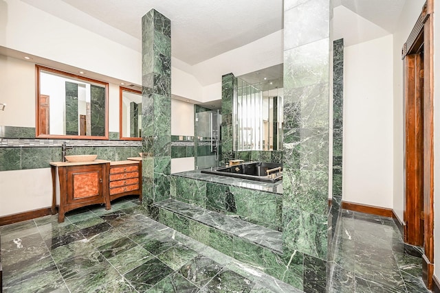 full bathroom with lofted ceiling, a garden tub, vanity, and tile walls