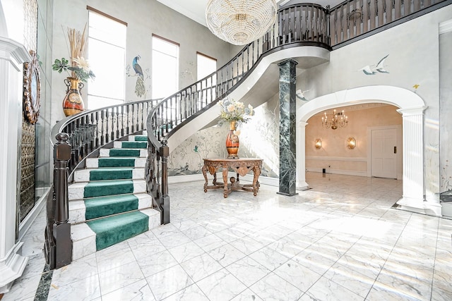 foyer entrance featuring arched walkways, marble finish floor, decorative columns, and a towering ceiling