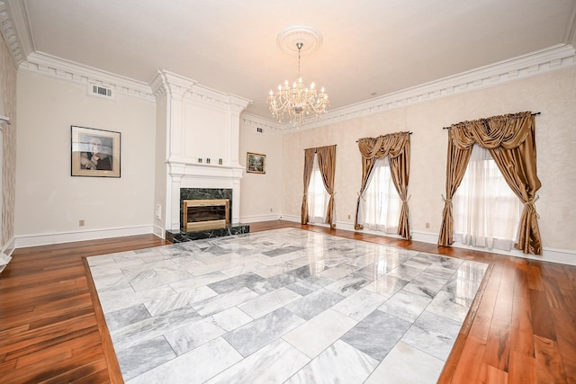 unfurnished living room featuring a notable chandelier, visible vents, baseboards, a high end fireplace, and hardwood / wood-style floors