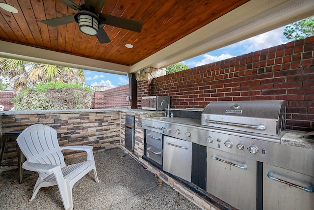 view of patio / terrace featuring an outdoor kitchen, a ceiling fan, area for grilling, fence, and a sink