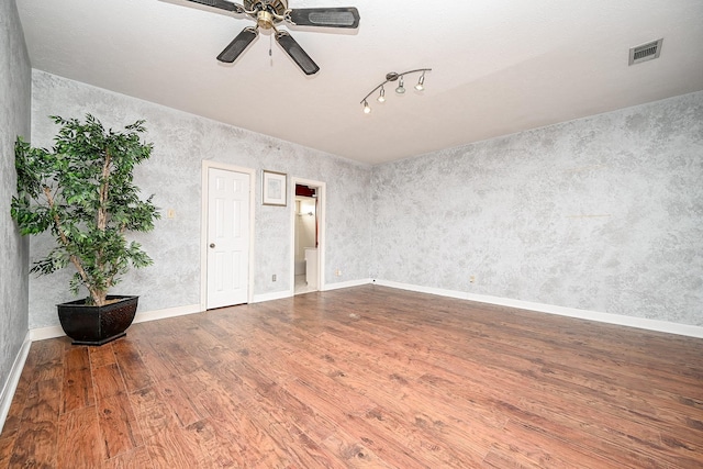 unfurnished room with a ceiling fan, wood finished floors, visible vents, and baseboards