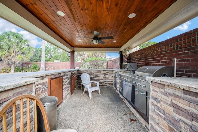 view of patio / terrace with a fenced backyard, ceiling fan, an outdoor kitchen, and area for grilling