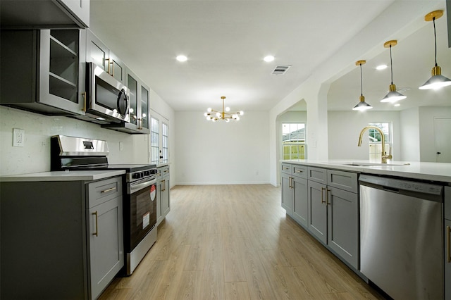 kitchen featuring light wood finished floors, visible vents, gray cabinets, stainless steel appliances, and a sink