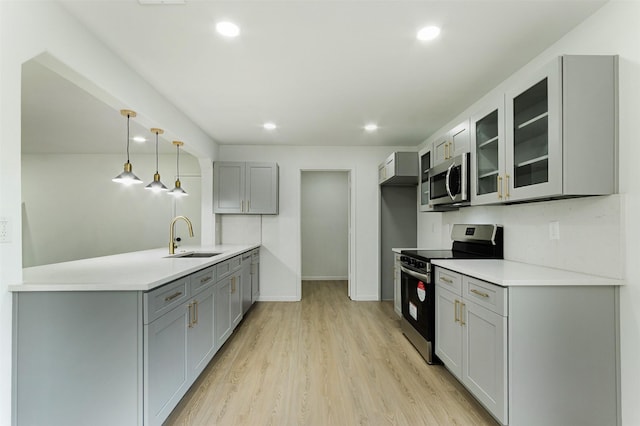 kitchen with a sink, stainless steel appliances, gray cabinetry, and a peninsula