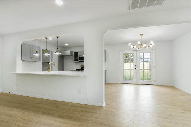 unfurnished living room featuring light wood-type flooring, visible vents, french doors, baseboards, and a chandelier