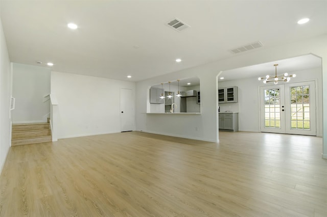 unfurnished living room with visible vents, light wood-style flooring, and stairway