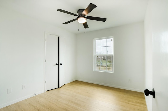 spare room with baseboards, light wood-style floors, and ceiling fan