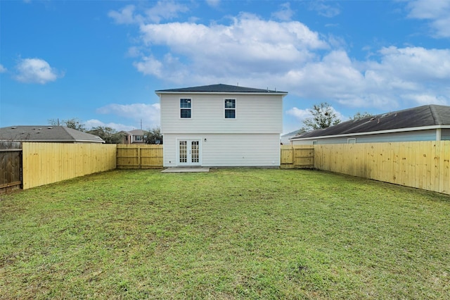 rear view of property with a fenced backyard, french doors, and a yard