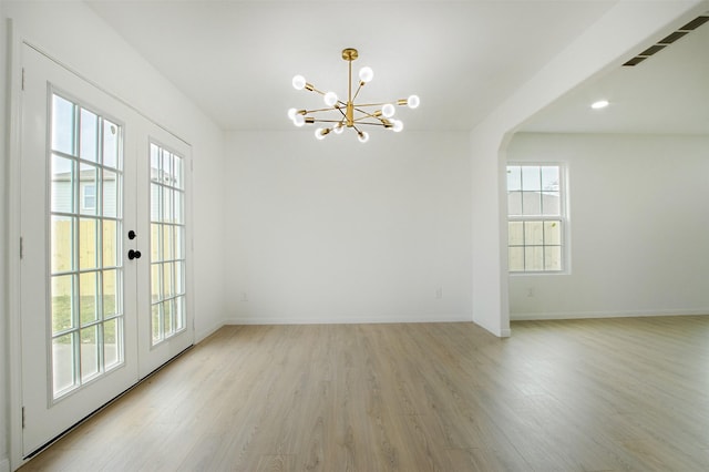 spare room with baseboards, visible vents, french doors, a notable chandelier, and light wood-type flooring