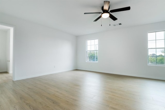 empty room with baseboards, visible vents, light wood finished floors, and ceiling fan