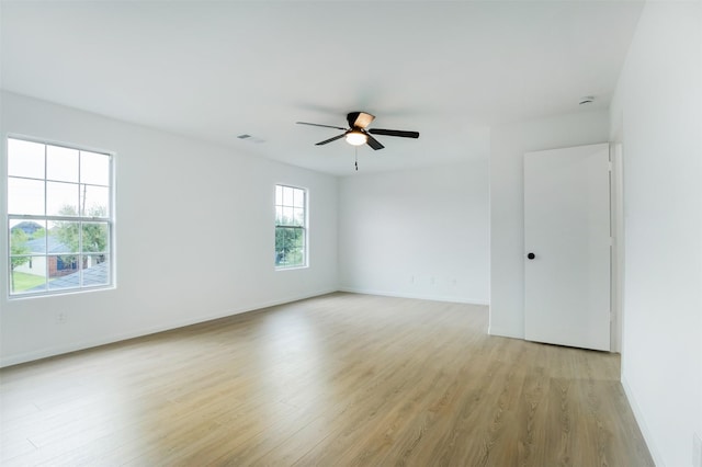 spare room featuring baseboards, a ceiling fan, visible vents, and light wood-type flooring