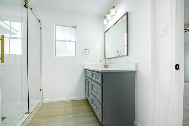 bathroom with a tile shower, baseboards, a wealth of natural light, and wood finished floors