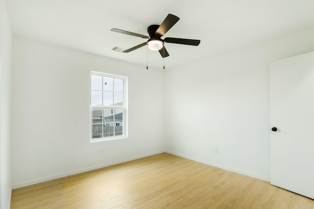 spare room with visible vents, light wood-style flooring, a ceiling fan, and baseboards