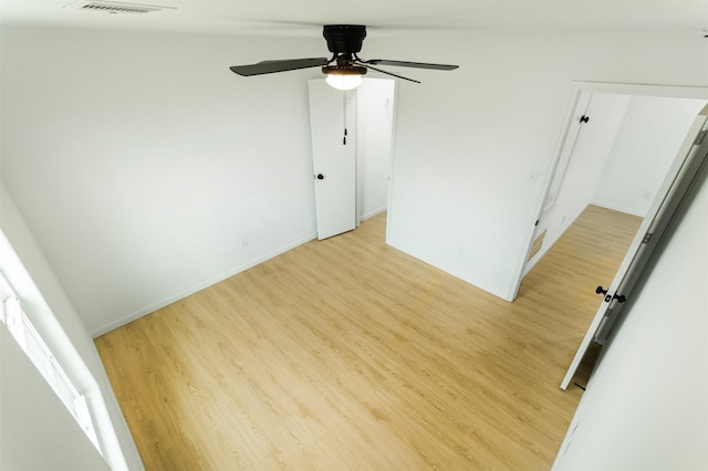 spare room featuring light wood-type flooring, baseboards, visible vents, and a ceiling fan