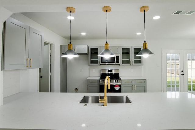 kitchen featuring visible vents, a sink, stainless steel appliances, glass insert cabinets, and french doors