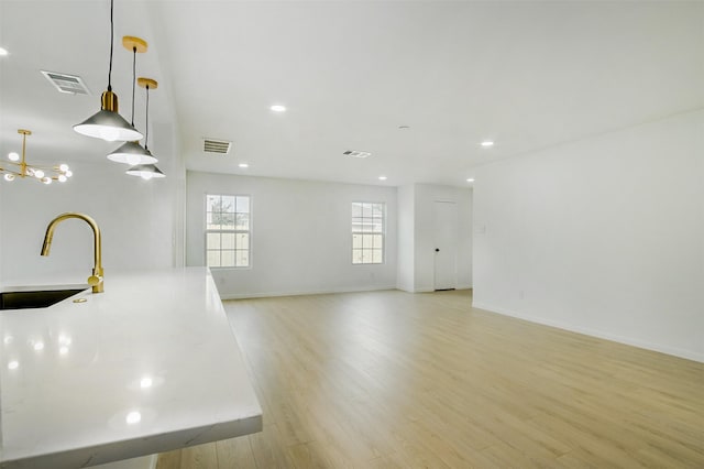 unfurnished room featuring visible vents, light wood-type flooring, and a sink