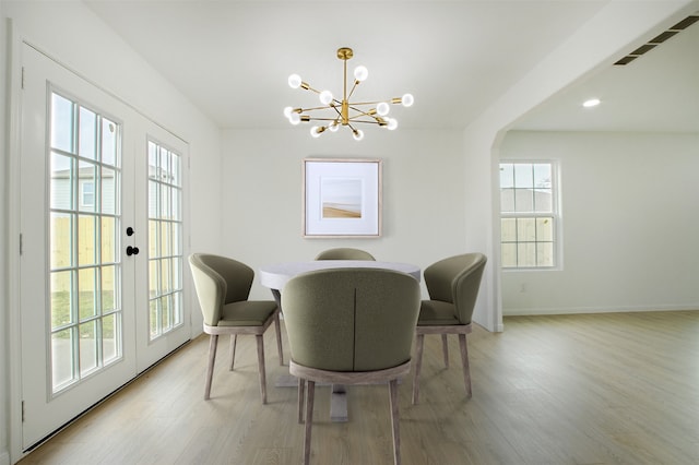 dining space with baseboards, visible vents, light wood finished floors, an inviting chandelier, and french doors