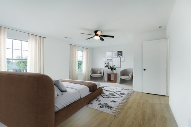 bedroom with a ceiling fan, wood finished floors, and visible vents