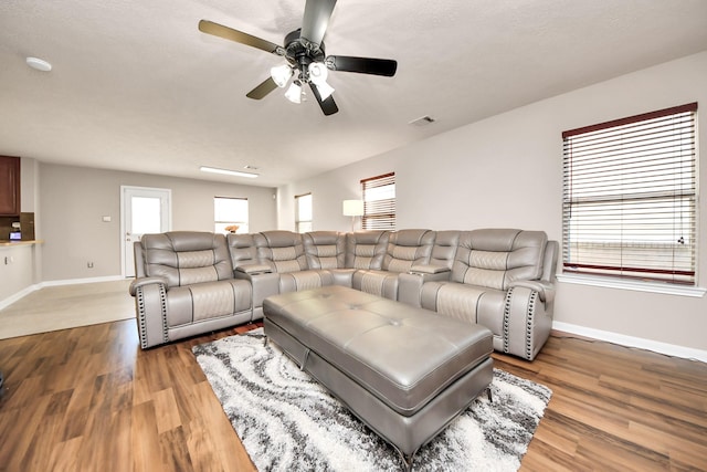 living area with a ceiling fan, baseboards, visible vents, and wood finished floors