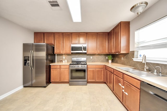 kitchen with appliances with stainless steel finishes, backsplash, a sink, and visible vents