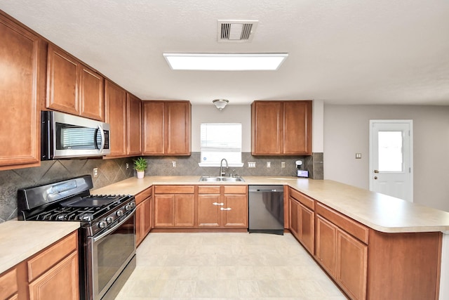 kitchen with light countertops, visible vents, appliances with stainless steel finishes, a sink, and a peninsula