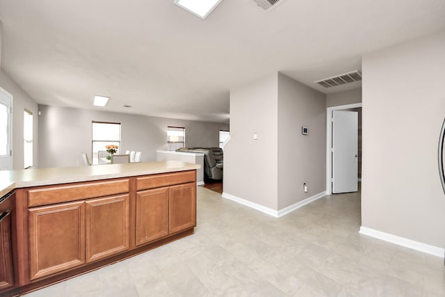 kitchen with brown cabinetry, light countertops, and visible vents