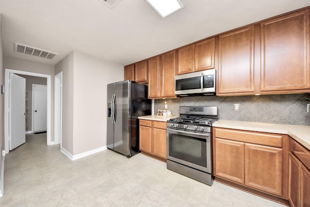 kitchen featuring stainless steel appliances, light countertops, visible vents, decorative backsplash, and baseboards