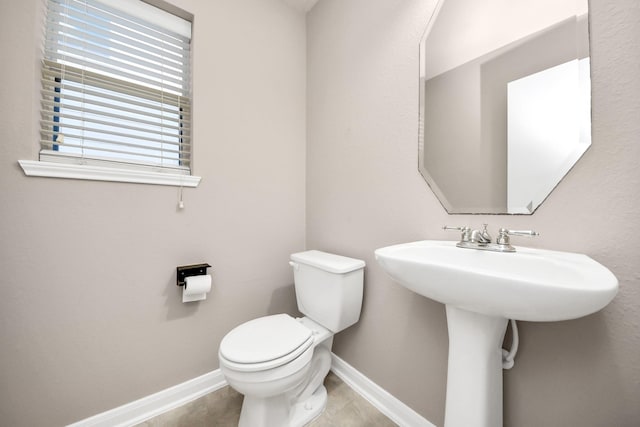 half bath featuring toilet, tile patterned flooring, and baseboards