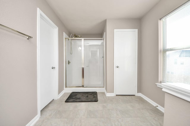 bathroom with a shower stall and baseboards