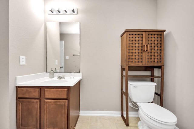 half bathroom with toilet, baseboards, and vanity