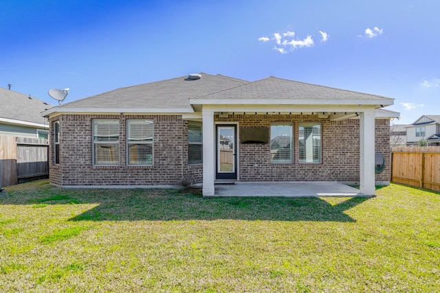 back of house featuring brick siding, a fenced backyard, a patio, and a yard