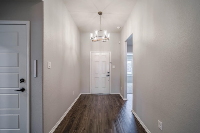 doorway featuring a chandelier, dark wood finished floors, and baseboards