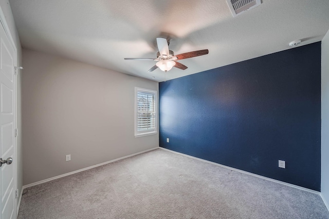 carpeted spare room featuring ceiling fan, a textured ceiling, visible vents, and baseboards