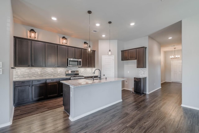 kitchen featuring dark wood finished floors, decorative backsplash, stainless steel appliances, dark brown cabinets, and a sink