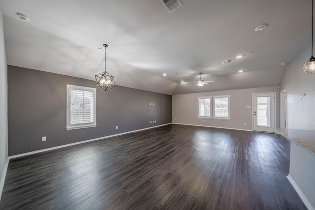 unfurnished room with dark wood-style flooring, lofted ceiling, visible vents, baseboards, and ceiling fan with notable chandelier