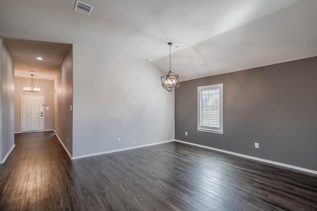 unfurnished room with visible vents, dark wood-type flooring, vaulted ceiling, a chandelier, and baseboards