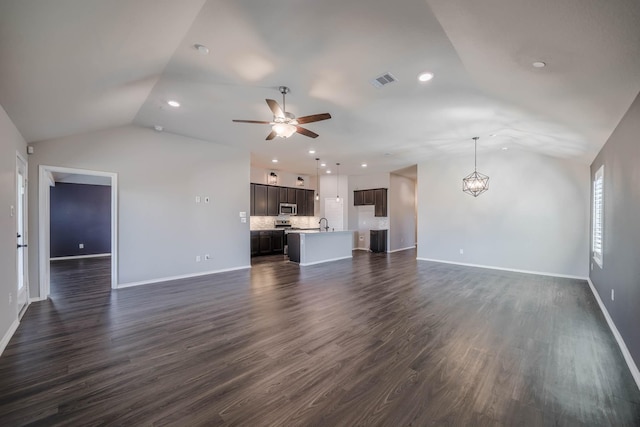 unfurnished living room featuring dark wood-style flooring, visible vents, vaulted ceiling, baseboards, and ceiling fan with notable chandelier