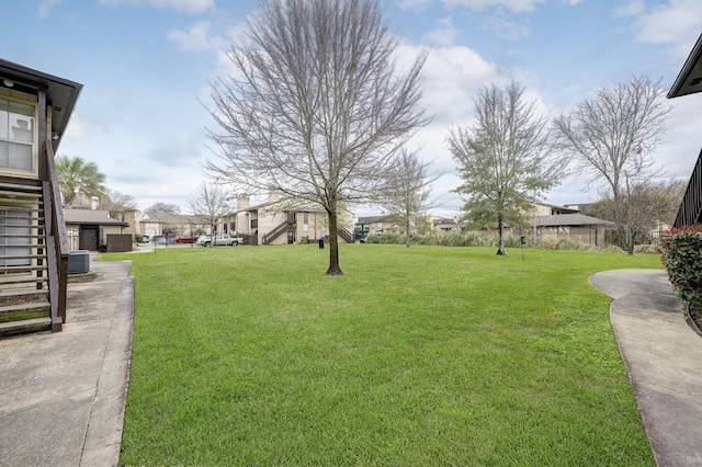 view of yard with stairs, a residential view, and central AC unit